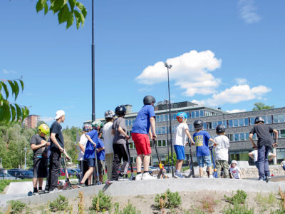 Barn och ungdomar åker kickbike på skatepark