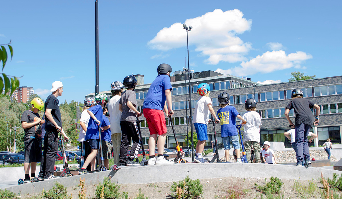 Barn och ungdomar åker kickbike på skatepark