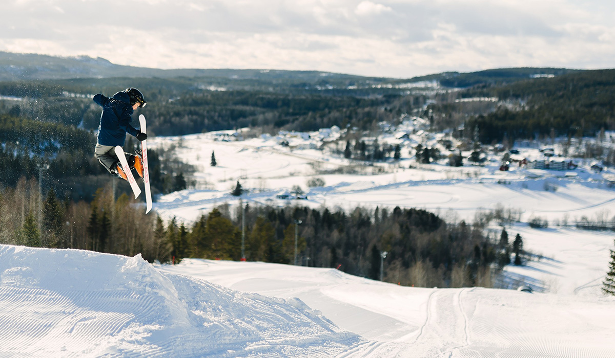 En pojke som hoppar med skidor i en skidbacke