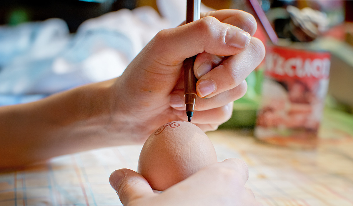 En person som målar på ett ägg.